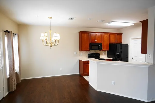 a view of kitchen with stainless steel appliances wooden floor and large window