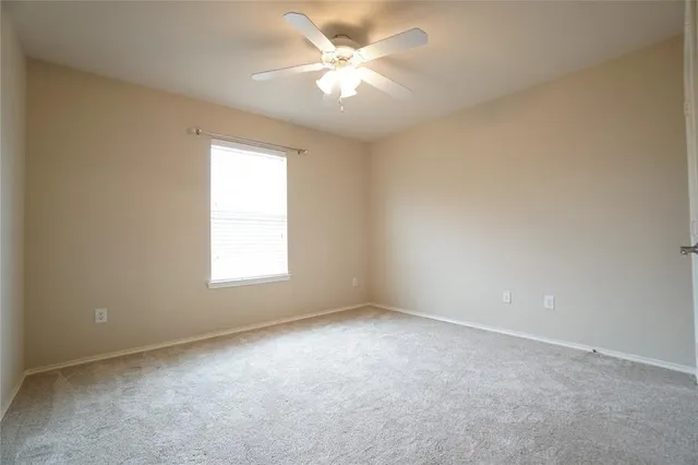 an empty room with a chandelier fan and windows