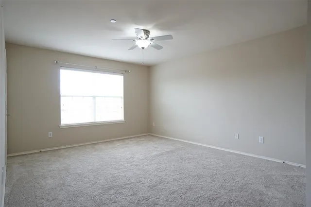 an empty room with a chandelier fan and windows