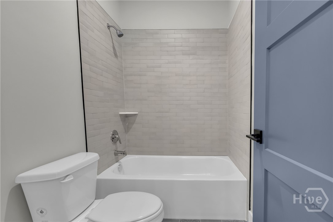2476 St Martin Way Monroe, GA 30656 - Photo 61 of 75 Bathroom featuring a white bathtub, subway tile surround, chrome shower fixtures, and a white toilet