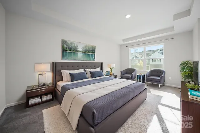a spacious bedroom with a bed a couch and potted plant with two windows