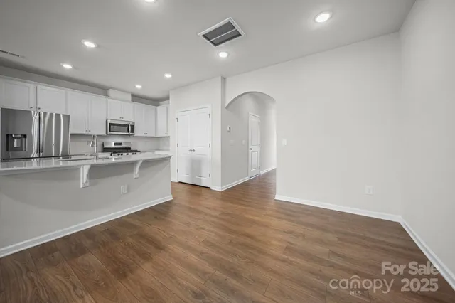 a kitchen with stainless steel appliances granite countertop a refrigerator a sink dishwasher and a oven with white cabinets