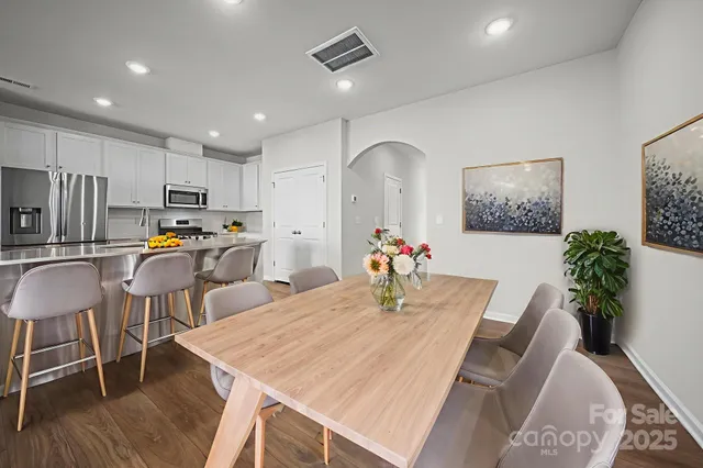 a kitchen with granite countertop kitchen island stainless steel appliances sink refrigerator dining table and chairs