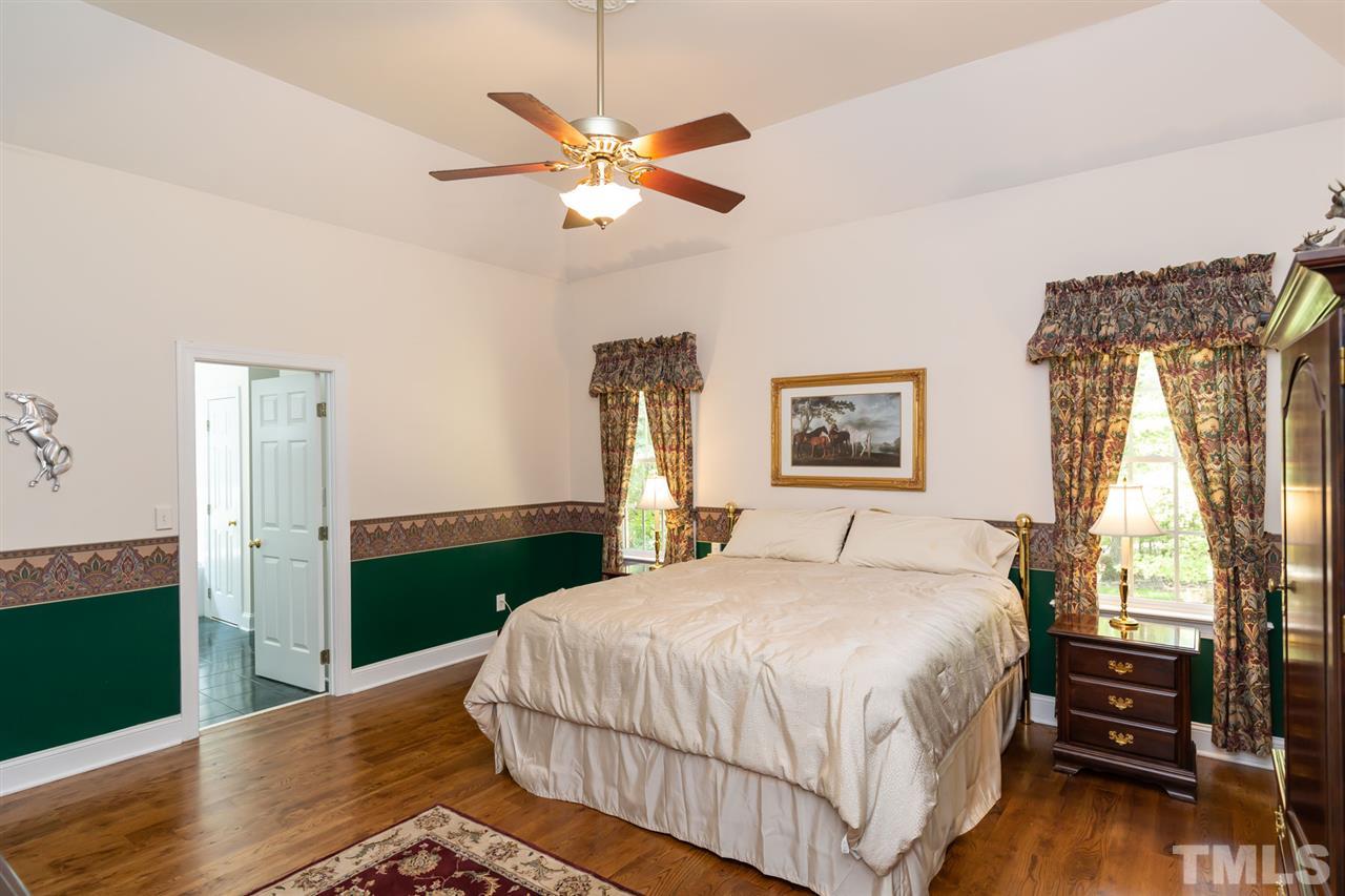 12613 Raven Ridge Road Raleigh, NC 27614 - Photo 14 of 29 a bedroom with a bed and a chandelier