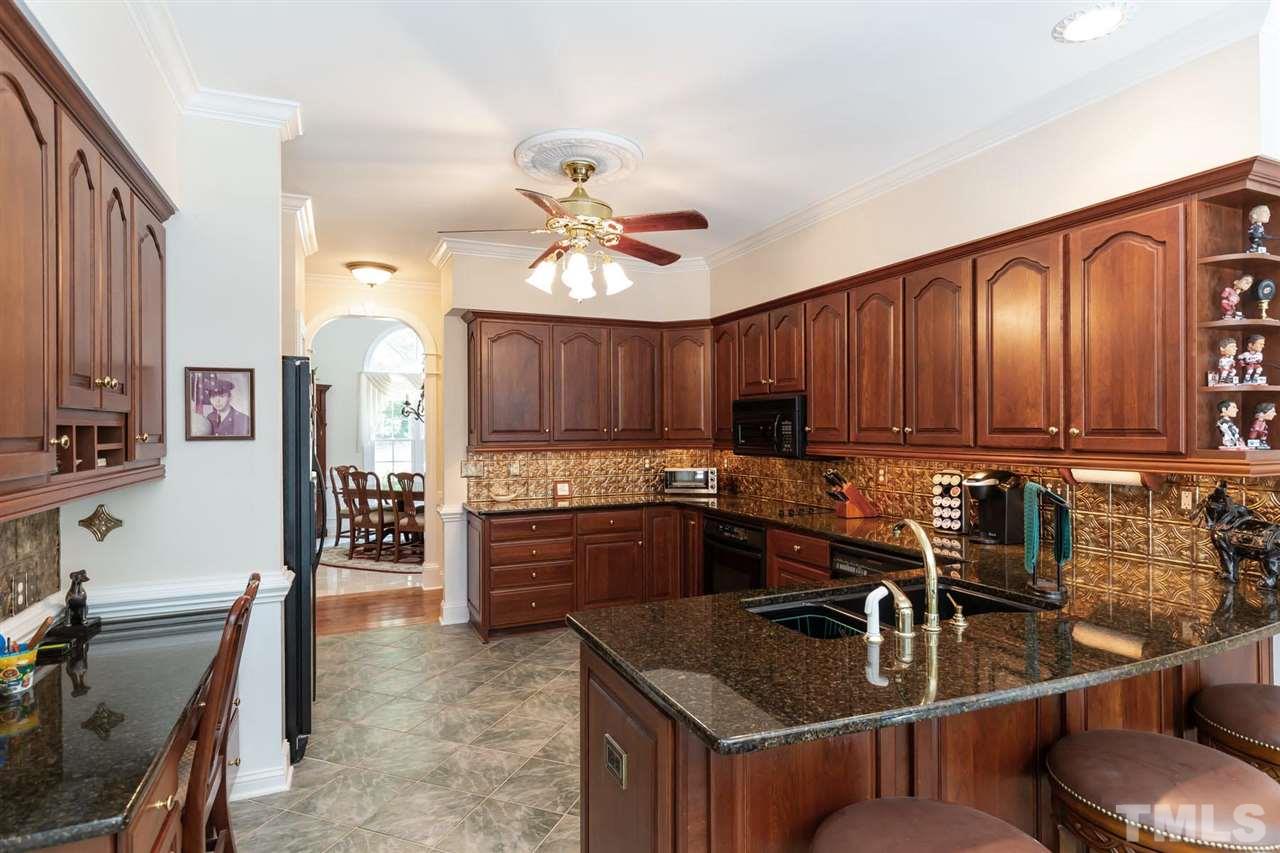 12613 Raven Ridge Road Raleigh, NC 27614 - Photo 9 of 29 a kitchen with kitchen island granite countertop a sink stove and cabinets