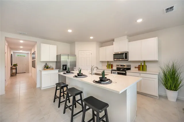 a view of a kitchen with kitchen island a sink stainless steel appliances and cabinets