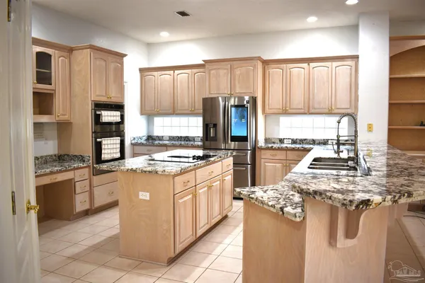 a kitchen with stainless steel appliances granite countertop a stove top oven a refrigerator a sink and dishwasher