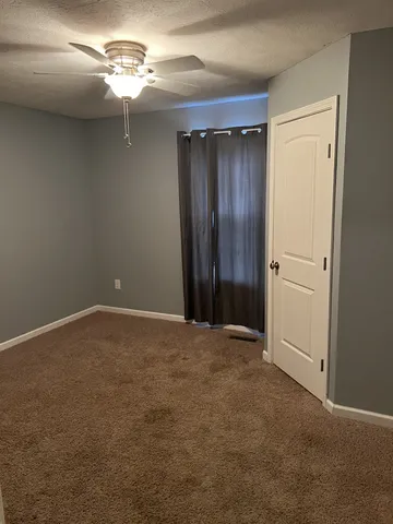 a view of an empty room with a chandelier fan