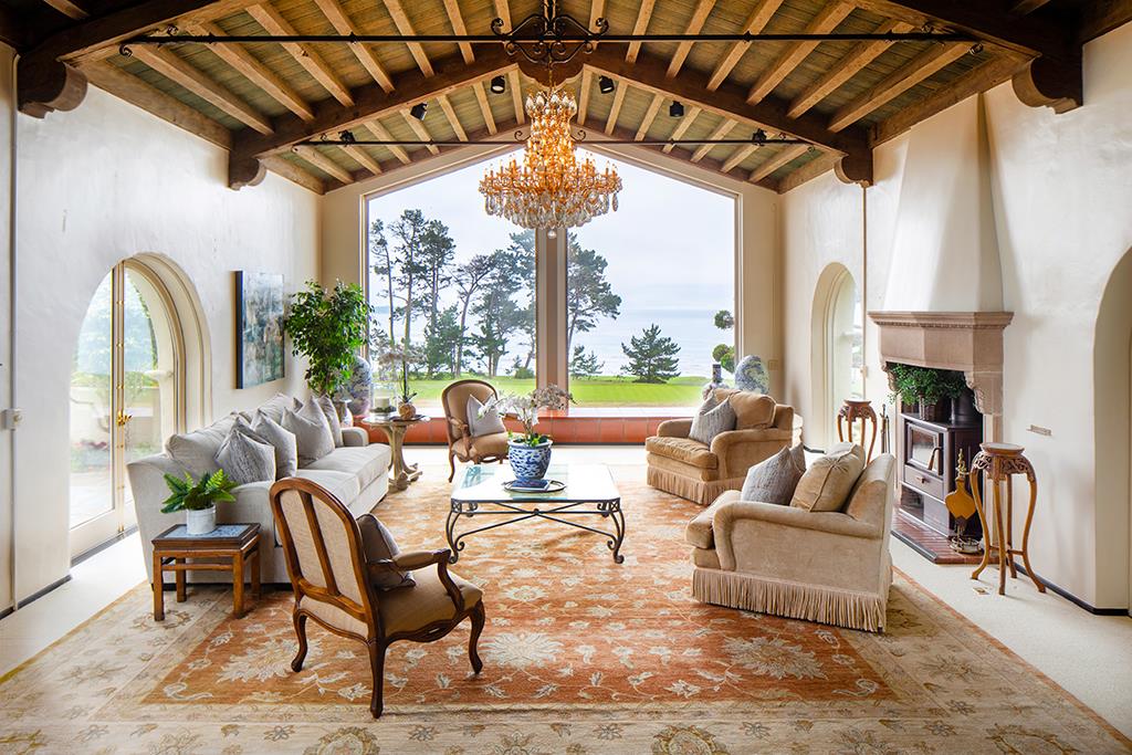 3406 17 Mile Drive Pebble Beach, CA 93953 - Photo 2 of 11 a living room with furniture a fireplace and a chandelier