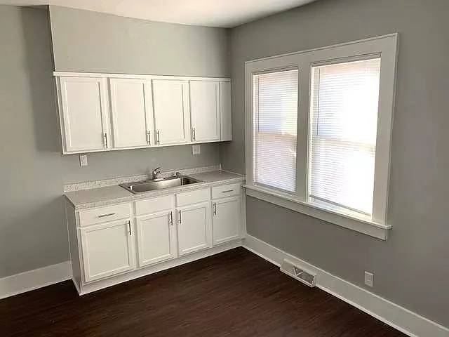 a view of a kitchen with wooden floor and a window