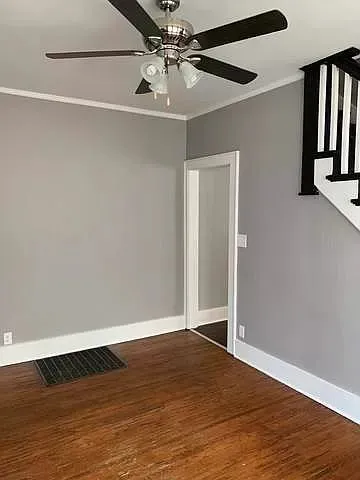 an empty room with wooden floor closet and windows