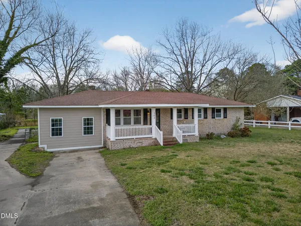 a front view of a house with a garden and trees