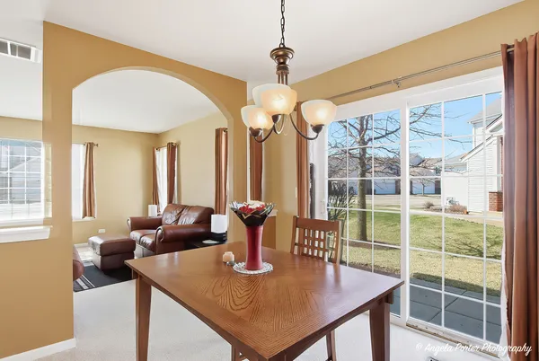 a kitchen with stainless steel appliances granite countertop a refrigerator a stove a sink dishwasher and wooden cabinets with a dining table