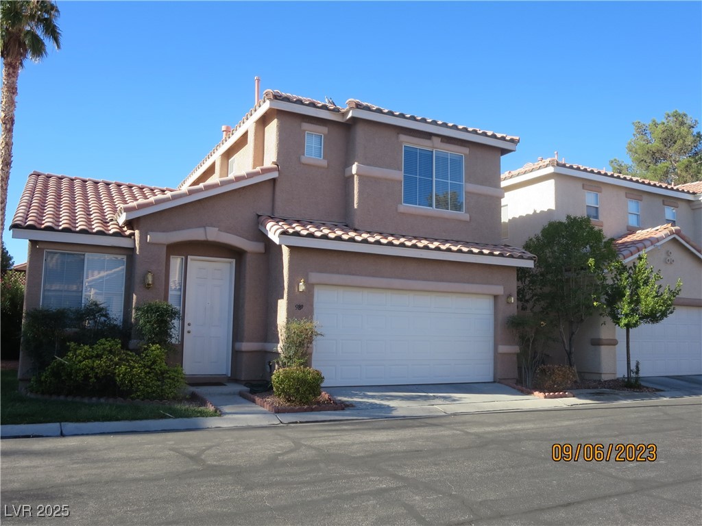 Mediterranean / spanish house with stucco siding, a tile roof, and a garage