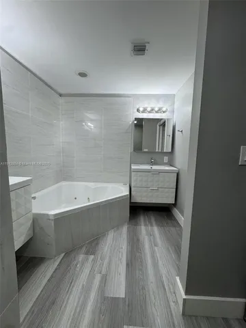 a bathroom with a tub sink and mirror