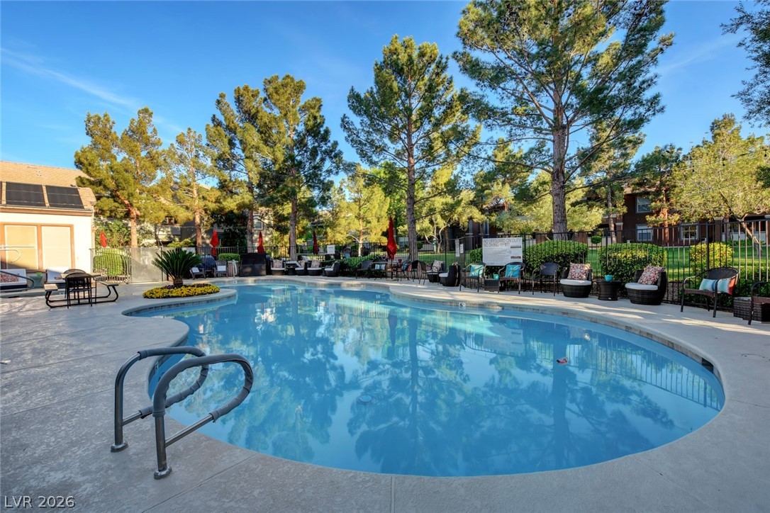 555 East Silverado Ranch Boulevard, Unit 2124 Las Vegas, NV 89183 - Photo 41 of 47 A refreshing community pool with ample seating, embraced by tall, verdant trees under a clear sky.