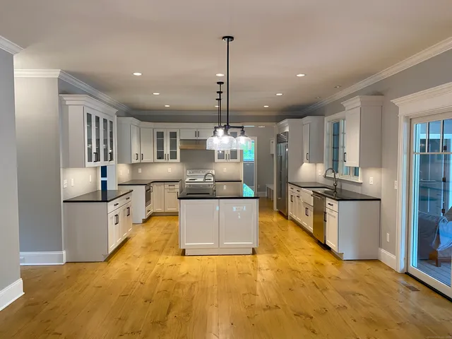 a large kitchen with stainless steel appliances kitchen island granite countertop a large counter top and a view of living room