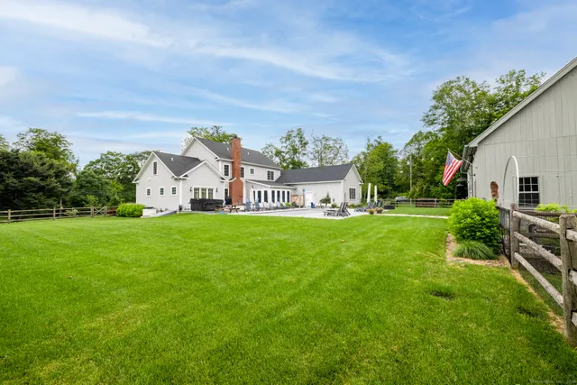a view of a white house with a big yard and potted plants
