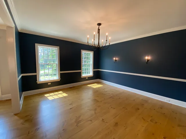 a view of an empty room with wooden floor and windows