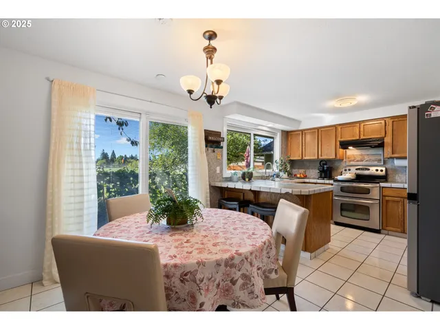 a kitchen with stainless steel appliances granite countertop a stove a refrigerator a sink dishwasher a dining table and chairs with wooden floor