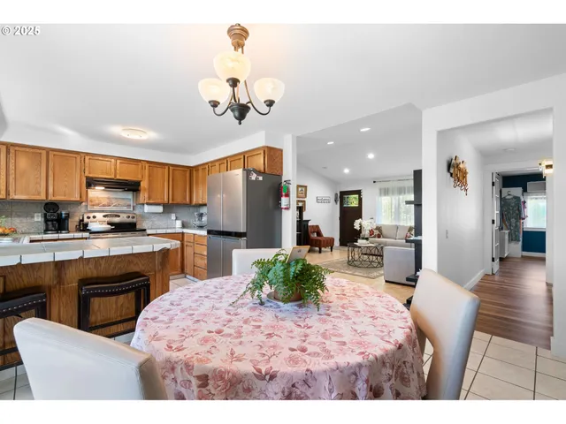 a kitchen with stainless steel appliances kitchen island granite countertop a refrigerator a stove a sink dishwasher and white cabinets with wooden floor
