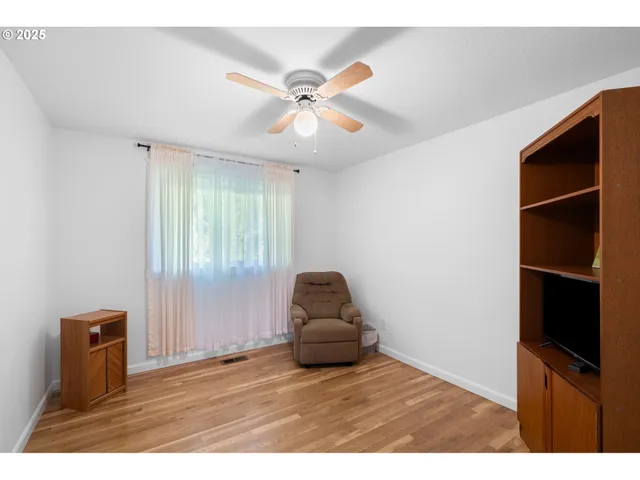 a living room with a flat screen tv with ceiling fan