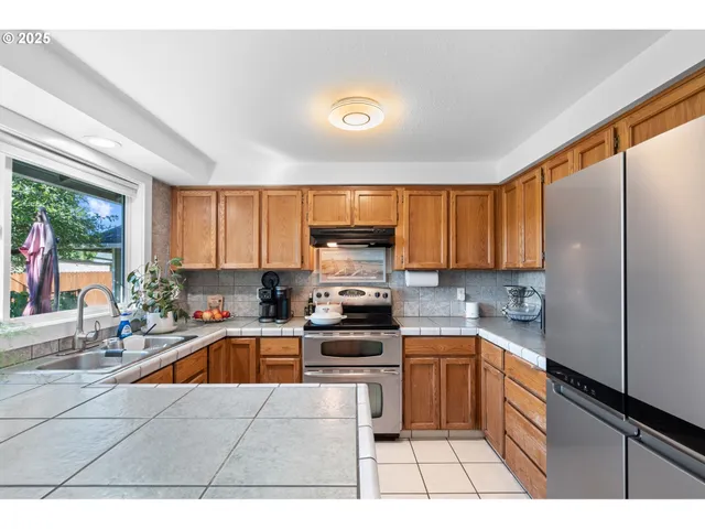 a kitchen with a sink a counter top space cabinets and stainless steel appliances