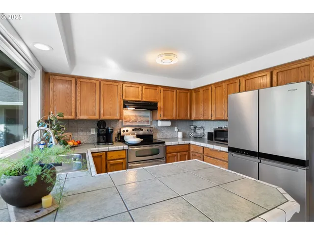 a kitchen with stainless steel appliances kitchen island granite countertop a refrigerator a stove top oven a sink dishwasher and white cabinets with wooden floor
