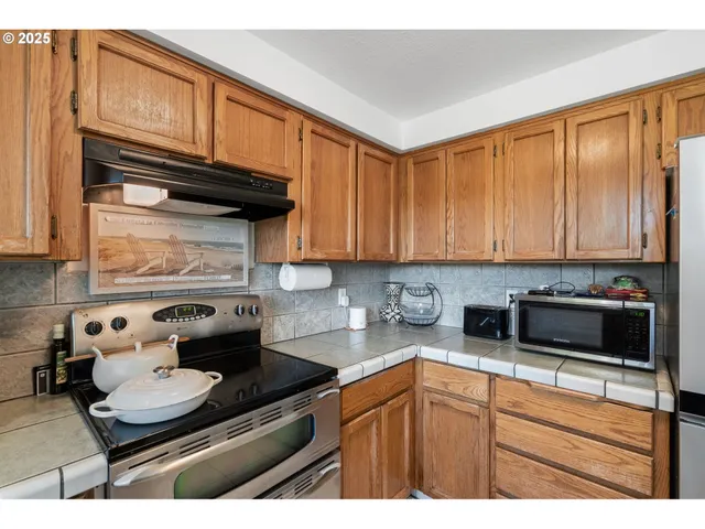 a kitchen with granite countertop stainless steel appliances a stove a sink and cabinets
