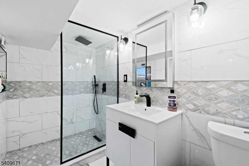 33 Mapes Avenue, Unit 2 Newark, NJ 07112 - Photo 15 of 40 a bathroom with a sink mirror and shower