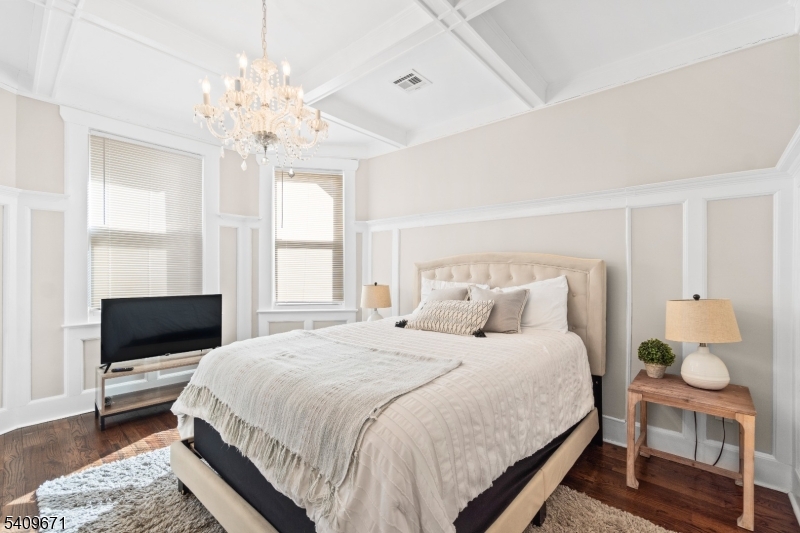 33 Mapes Avenue, Unit 2 Newark, NJ 07112 - Photo 31 of 40 a bedroom with a bed a chandelier and a flat tv screen