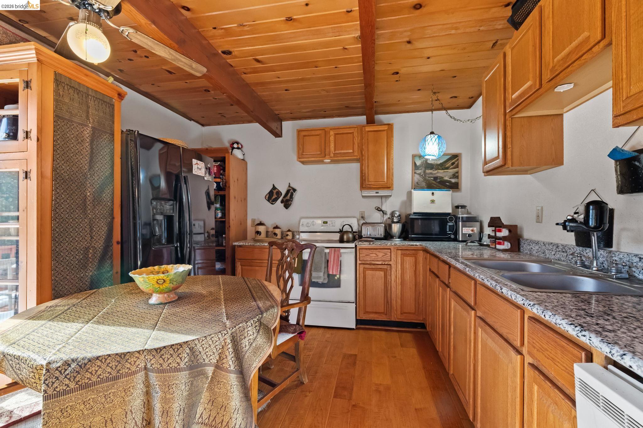 26039 Long Barn Road Long Barn, CA 95335 - Photo 11 of 27 Kitchen with a wooden ceiling with exposed beams, black fridge with ice dispenser, white electric range oven, light wood-style flooring, and light stone countertops