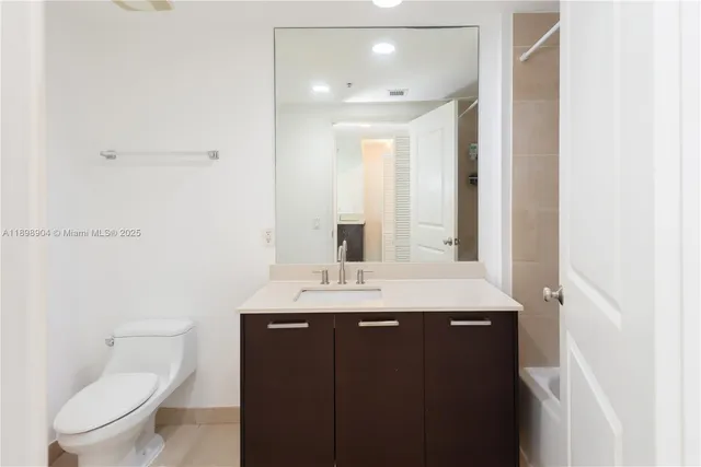 a bathroom with a granite countertop sink a toilet and a mirror