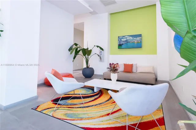 a living room with kitchen view and a potted plant