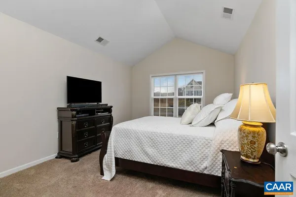 a bedroom with a bed and a flat tv screen on a dresser
