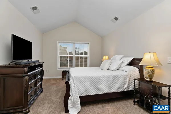 a bedroom with a bed and a flat tv screen on a dresser