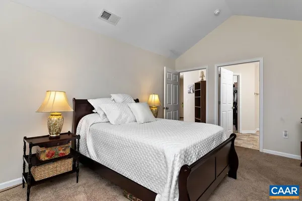 a bedroom with a bed a lamp and a large mirror