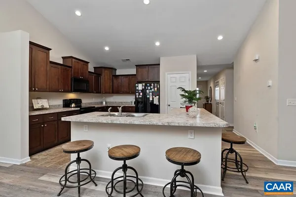 a kitchen with stainless steel appliances granite countertop a dining table chairs sink and cabinets