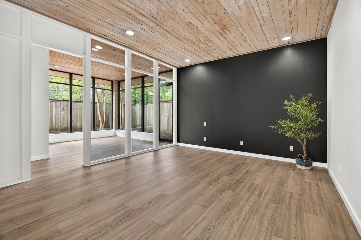 147 Valley Drive Liberty, TX 77575 - Photo 25 of 42 The primary bedroom features elegant luxury vinyl plank flooring, large windows, and a striking wood-paneled ceiling.