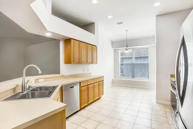 a kitchen with stainless steel appliances granite countertop a stove top oven a sink dishwasher a refrigerator and a oven with wooden floor