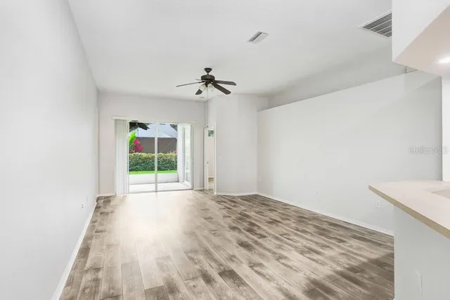 a view of empty room with wooden floor and fan