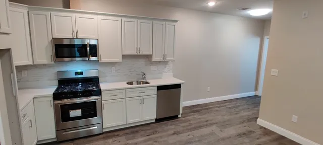 a kitchen with granite countertop white cabinets and stainless steel appliances