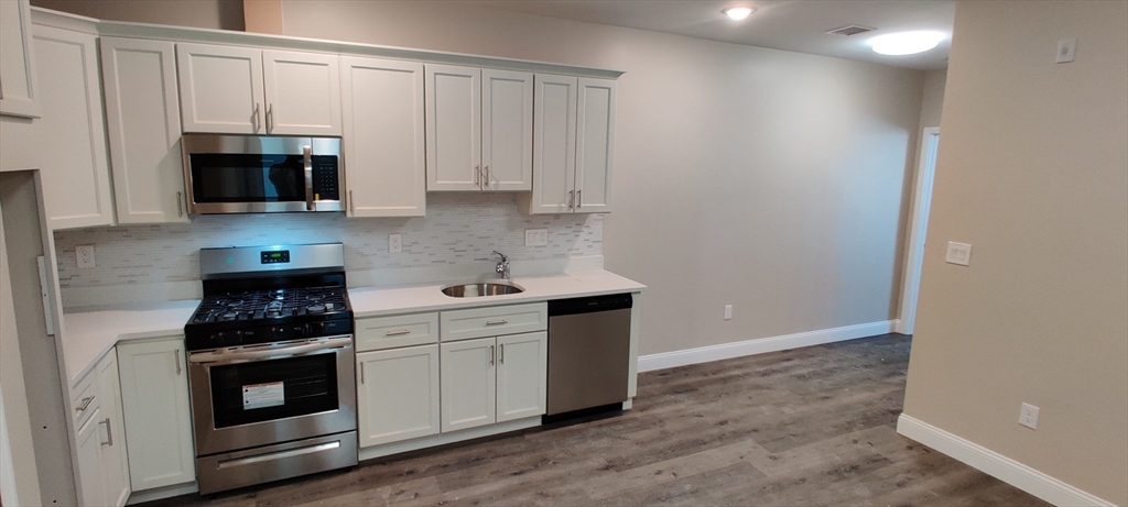 a kitchen with granite countertop white cabinets and stainless steel appliances