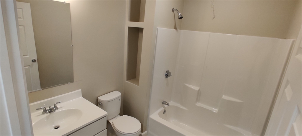 191 North Common Street, Unit 305 Lynn, MA 01905 - Photo 5 of 8 a white toilet sitting next to a bathroom sink and tub