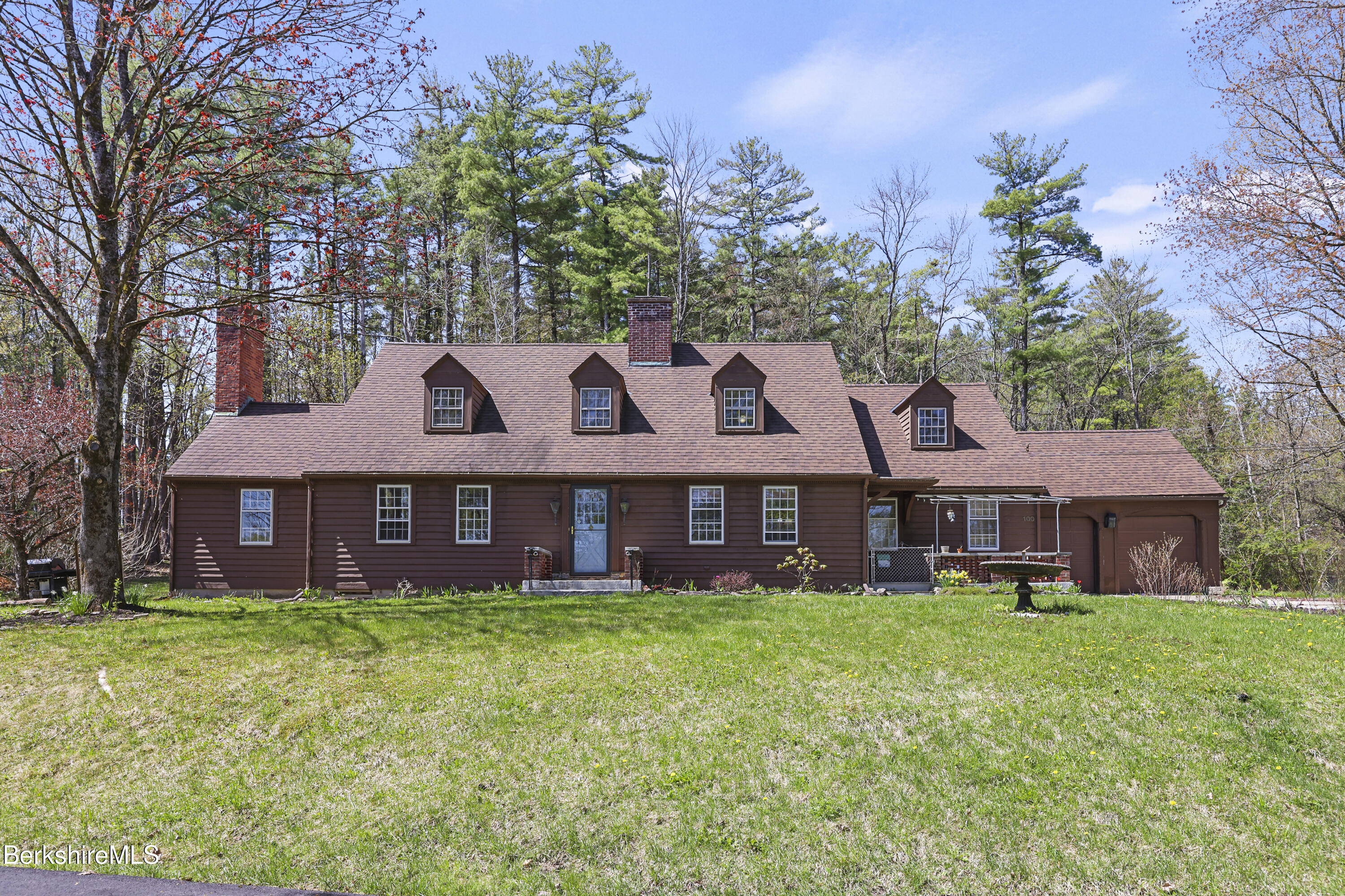 a view of a brick house with a big yard and large trees