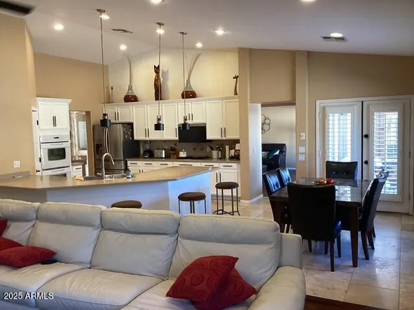 a living room with furniture kitchen area and a wooden floor