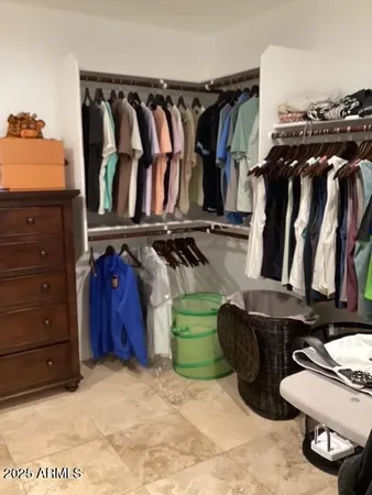 a view of walk in closet with clothes and shoes