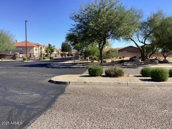 a view of a white house with a fountain plants and large tree