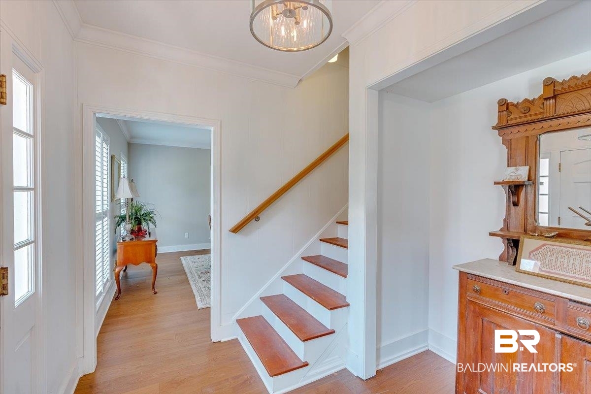 14160 Moffett Road Wilmer, AL 36587 - Photo 34 of 75 Stairs with baseboards, wood finished floors, ornamental molding, and an inviting chandelier