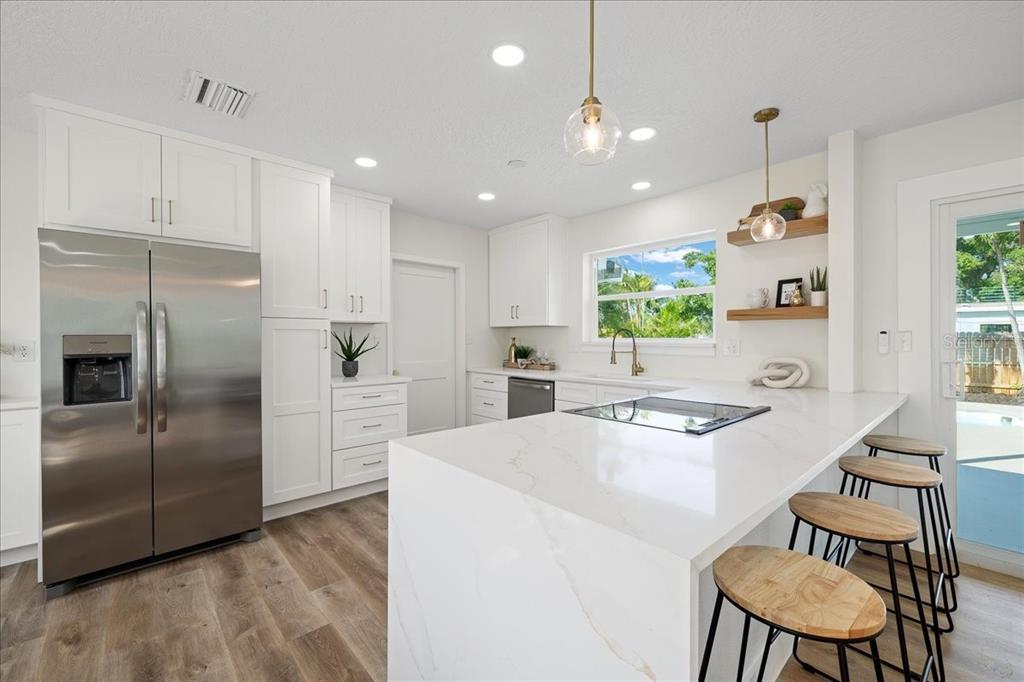 145 Southeast 3rd Street Satellite Beach, FL 32937 - Photo 5 of 29 a kitchen with stainless steel appliances kitchen island granite countertop a refrigerator and a stove top oven